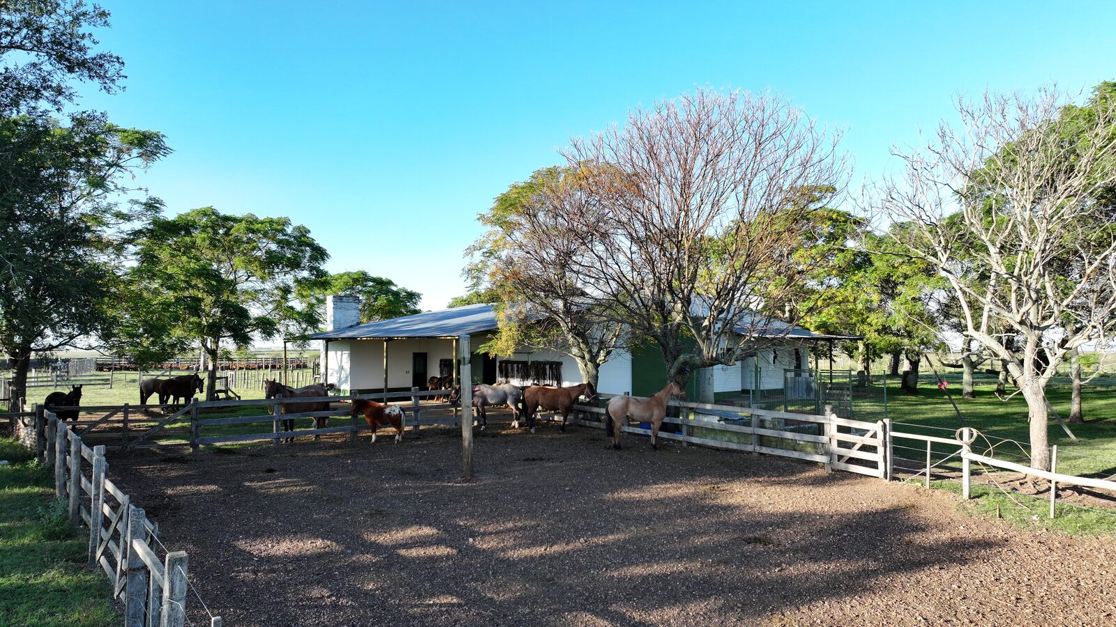 Currais e mangueiras com a sede da estância ao fundo