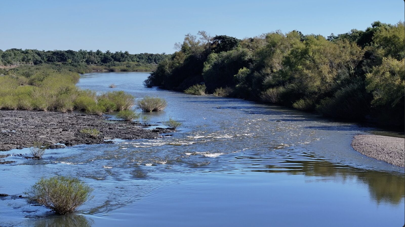 Rio na divisa da El Ceibo, com correnteza e mata nativa nas margens